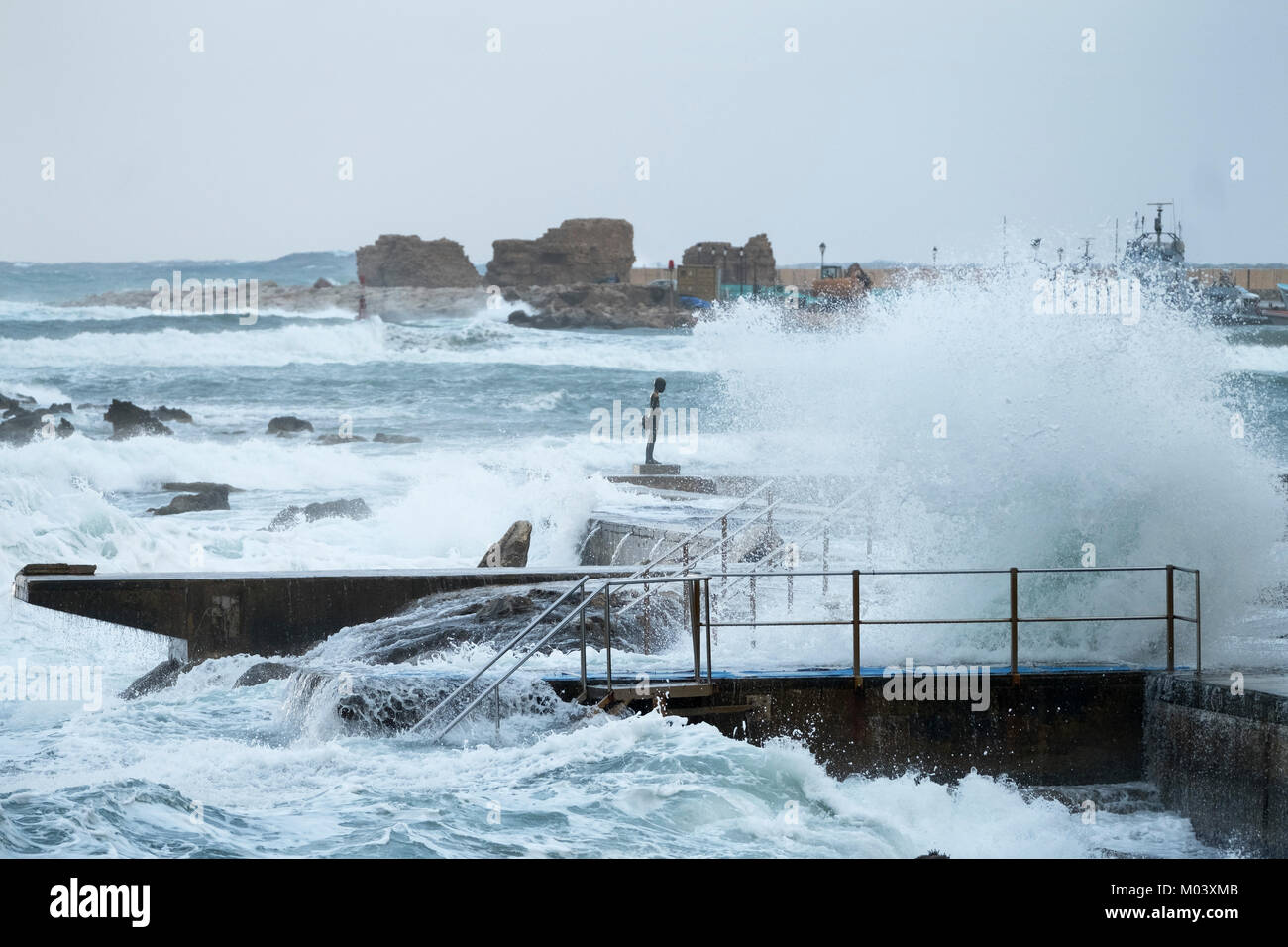 Paphos, Cyprus. 18th Jan, 2018. The little fisherman”- a bronze of a young boy and a large fish by Paphos artist, Yiota Ioannidou is battered by large waves in Paphos harbour, Republic of Cyprus. Picture Credit: Ian Rutherford/Alamy Live News Stock Photo