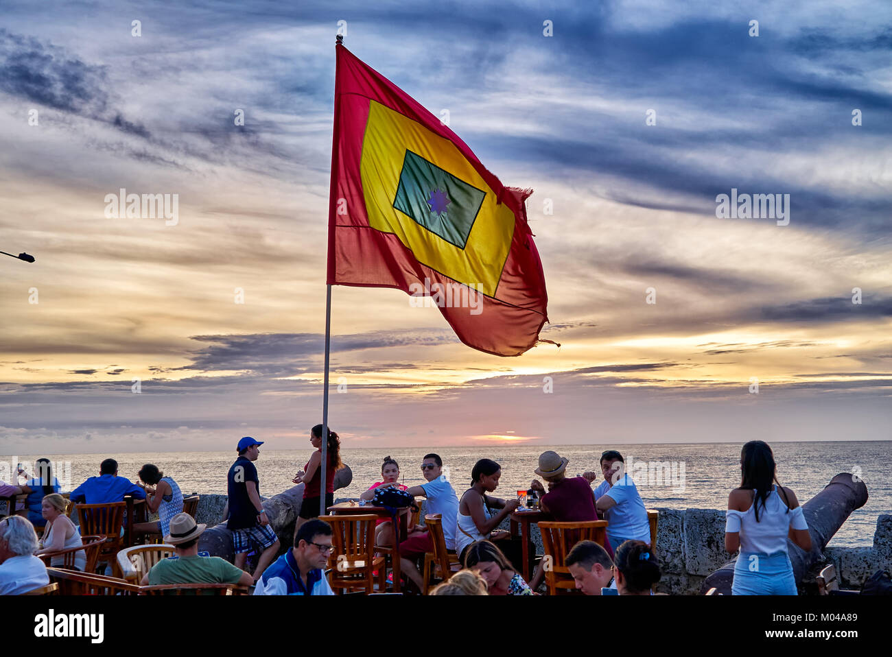 waving flag of Cartagena at sunset at Cafe del Mar Stock Photo