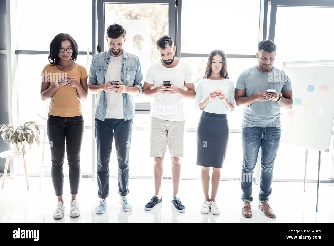 Young people focusing on their smartphones in office Stock Photo Alamy