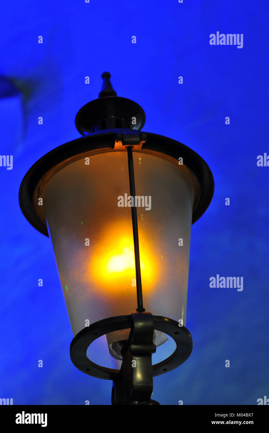 an old fashioned street lamp or lantern glowing in the early evening