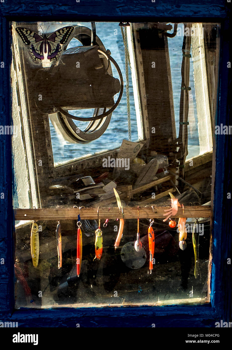 fishing lures hanging inside window of fishing boat cabin Stock Photo