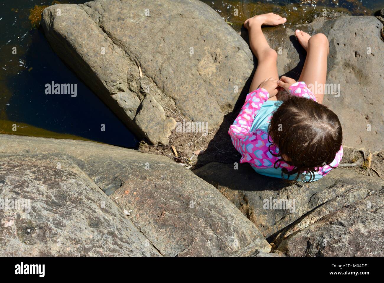 Child sitting on rocks next to a river photographed from above, Bowling ...