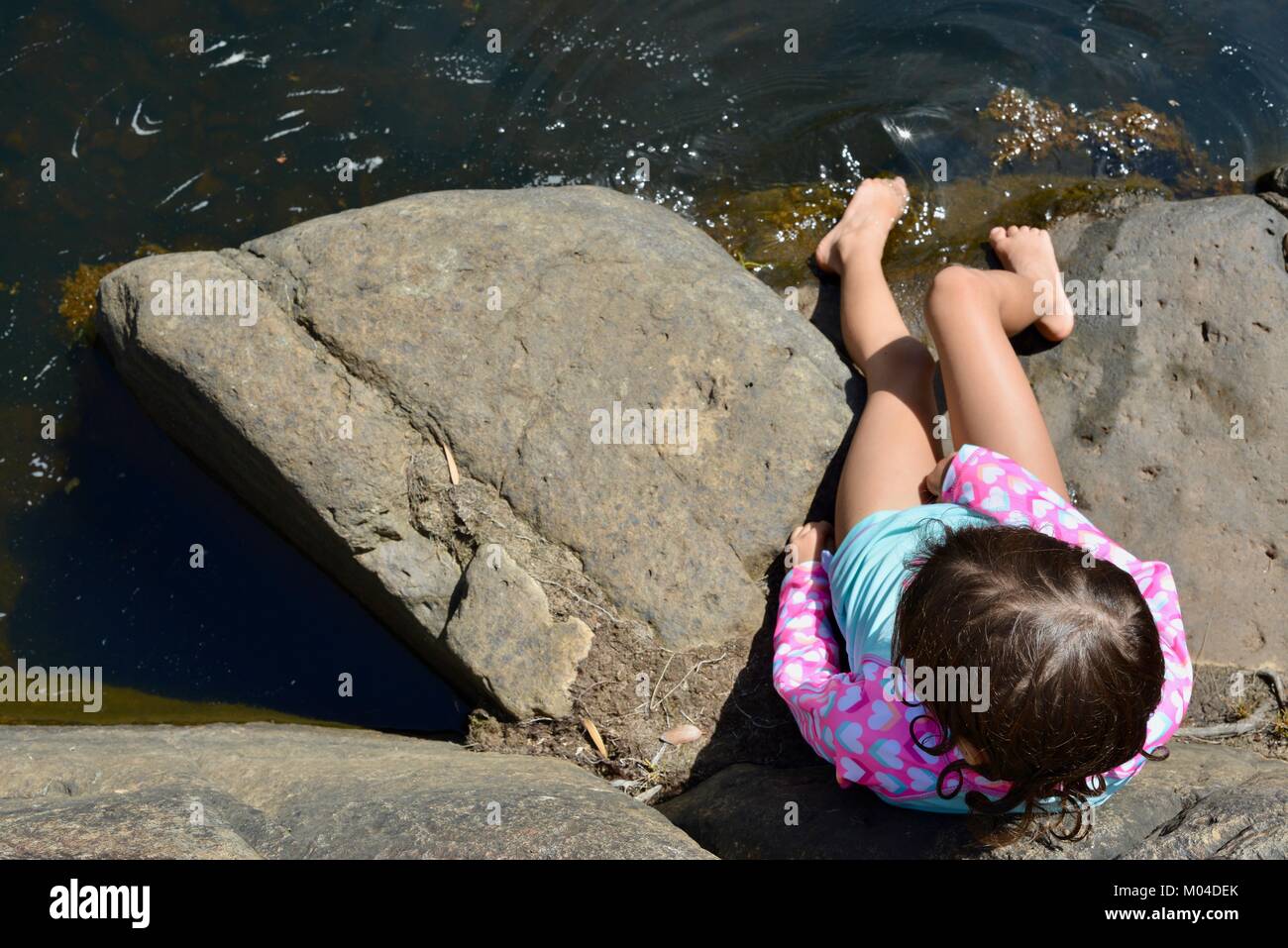 Child sitting on rocks next to a river photographed from above, Bowling ...