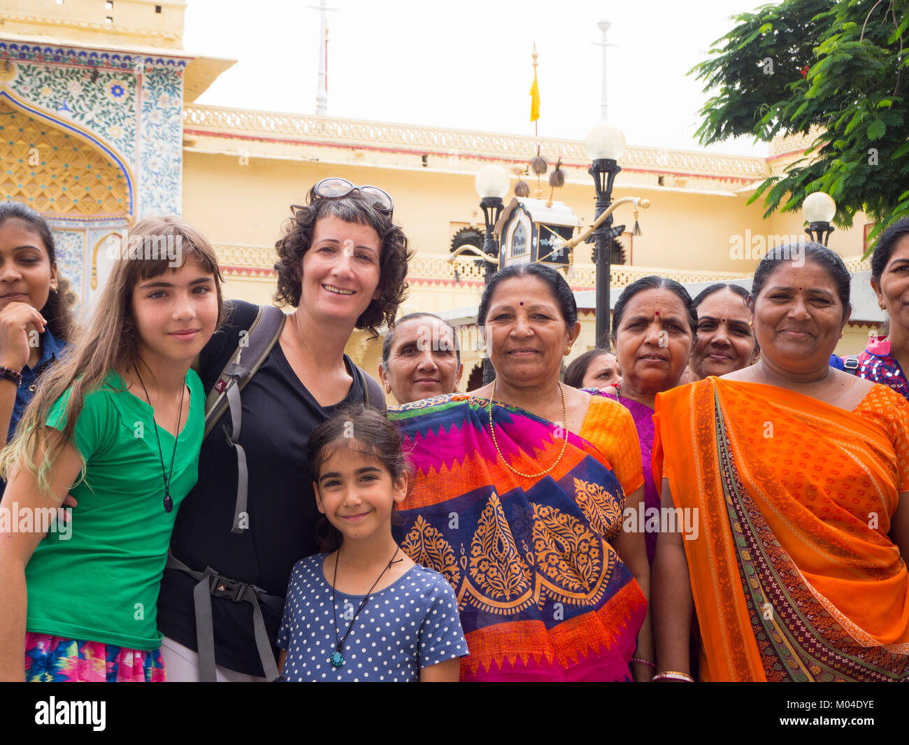 travelers  - mother and her two daughters standing taking picture with locals Stock Photo