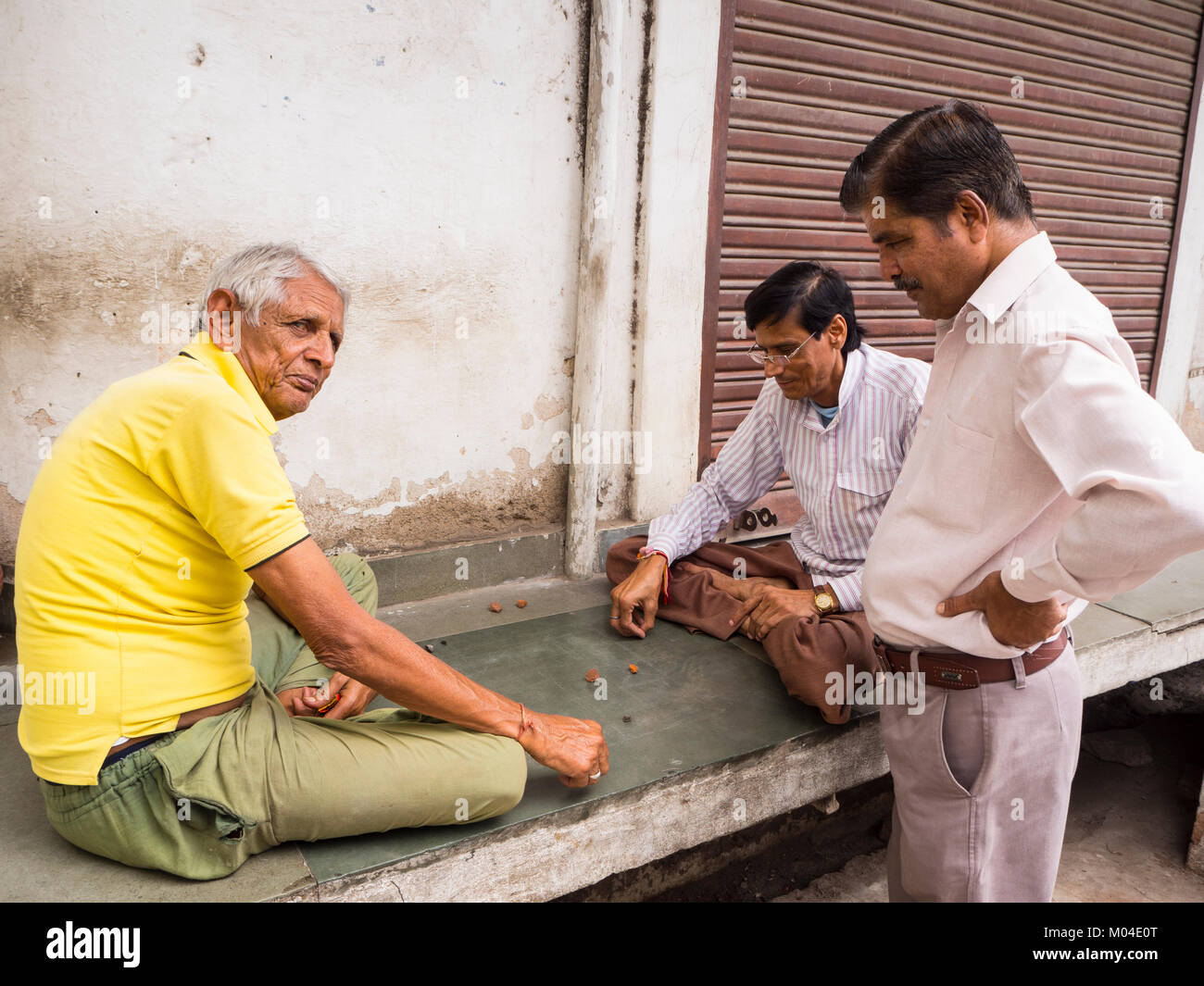 A photo of everyday life in the city - three nice Indian men who spend time together playing traditional street game in Rajasthan India Stock Photo