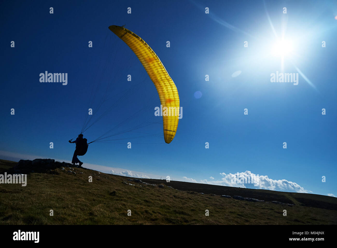 Paragliders on a mountain top preparing to take flight flying over a mountain valley in summer Stock Photo