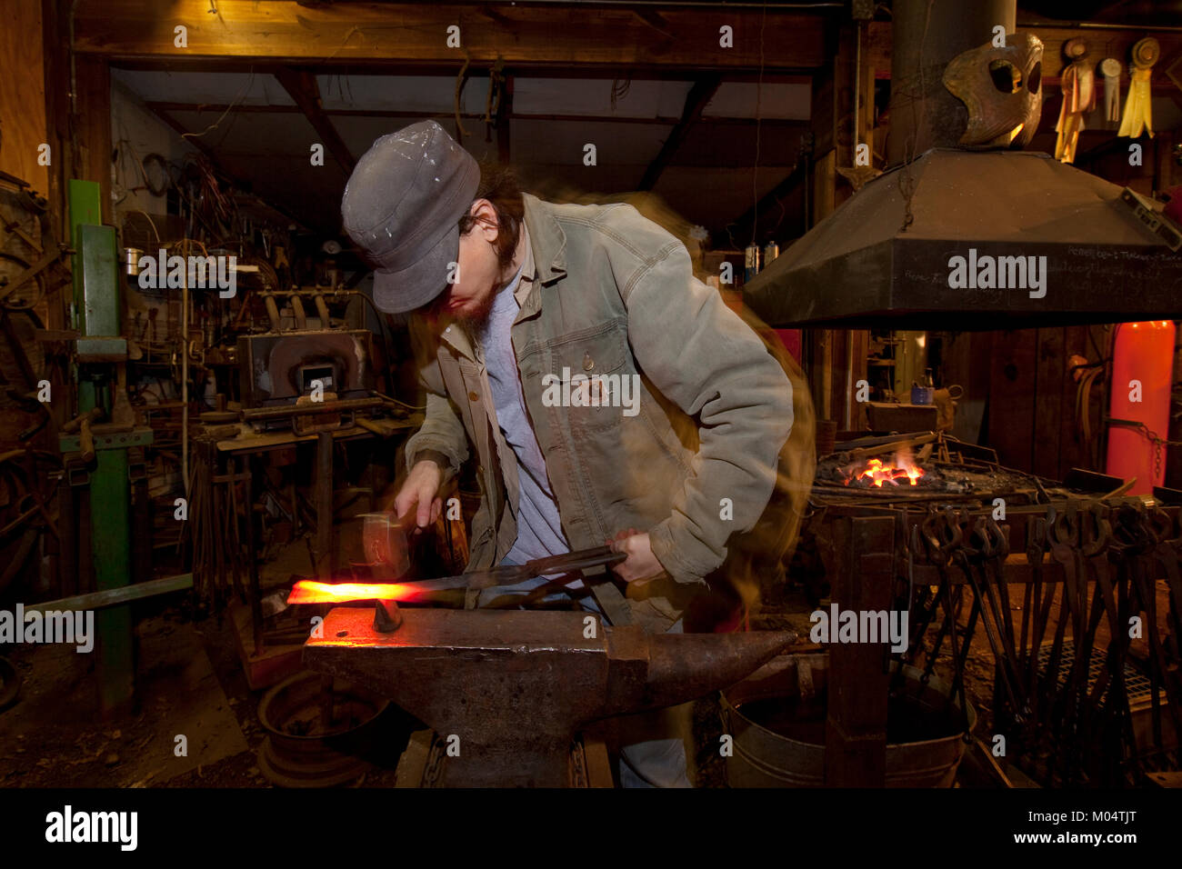 Blacksmith pounds heated metal Stock Photo