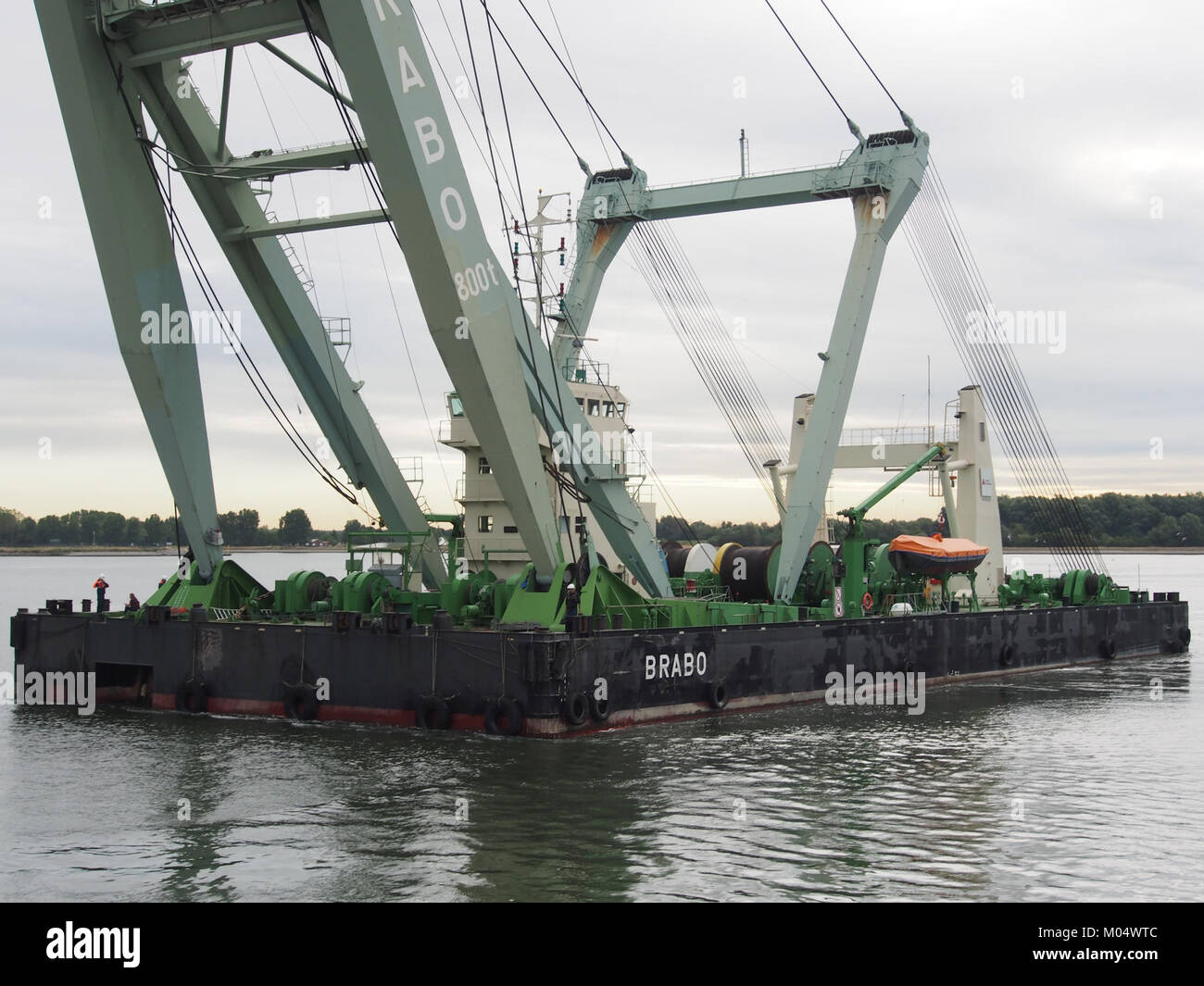 The Brabo 800T barge crane, identified by ENI 06105424, operates at the Port of Antwerp, facilitating the loading and unloading of heavy cargo. The crane is part of the port's extensive infrastructure. Stock Photo