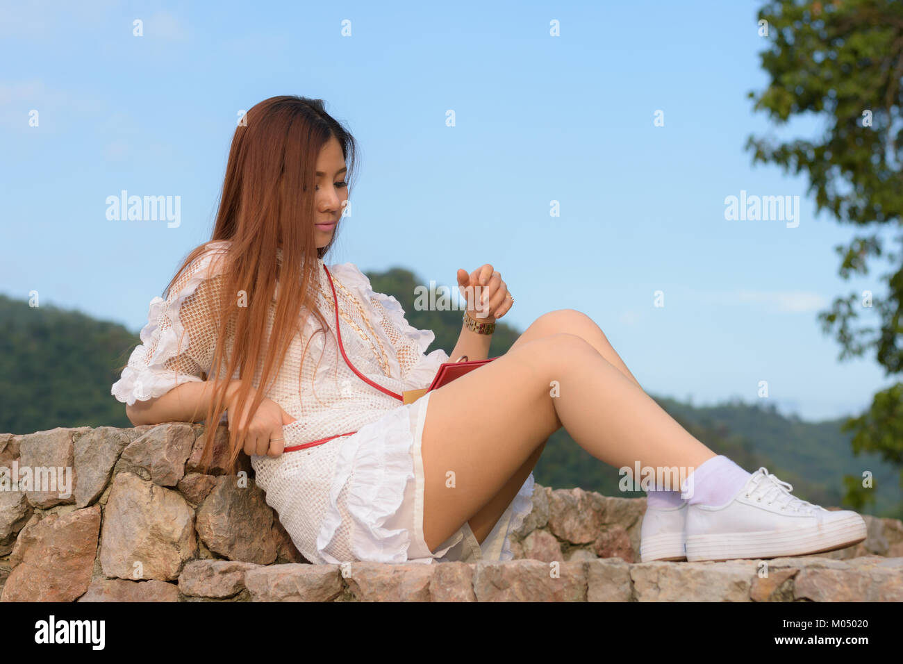 woman sitting on a rock wall Stock Photo