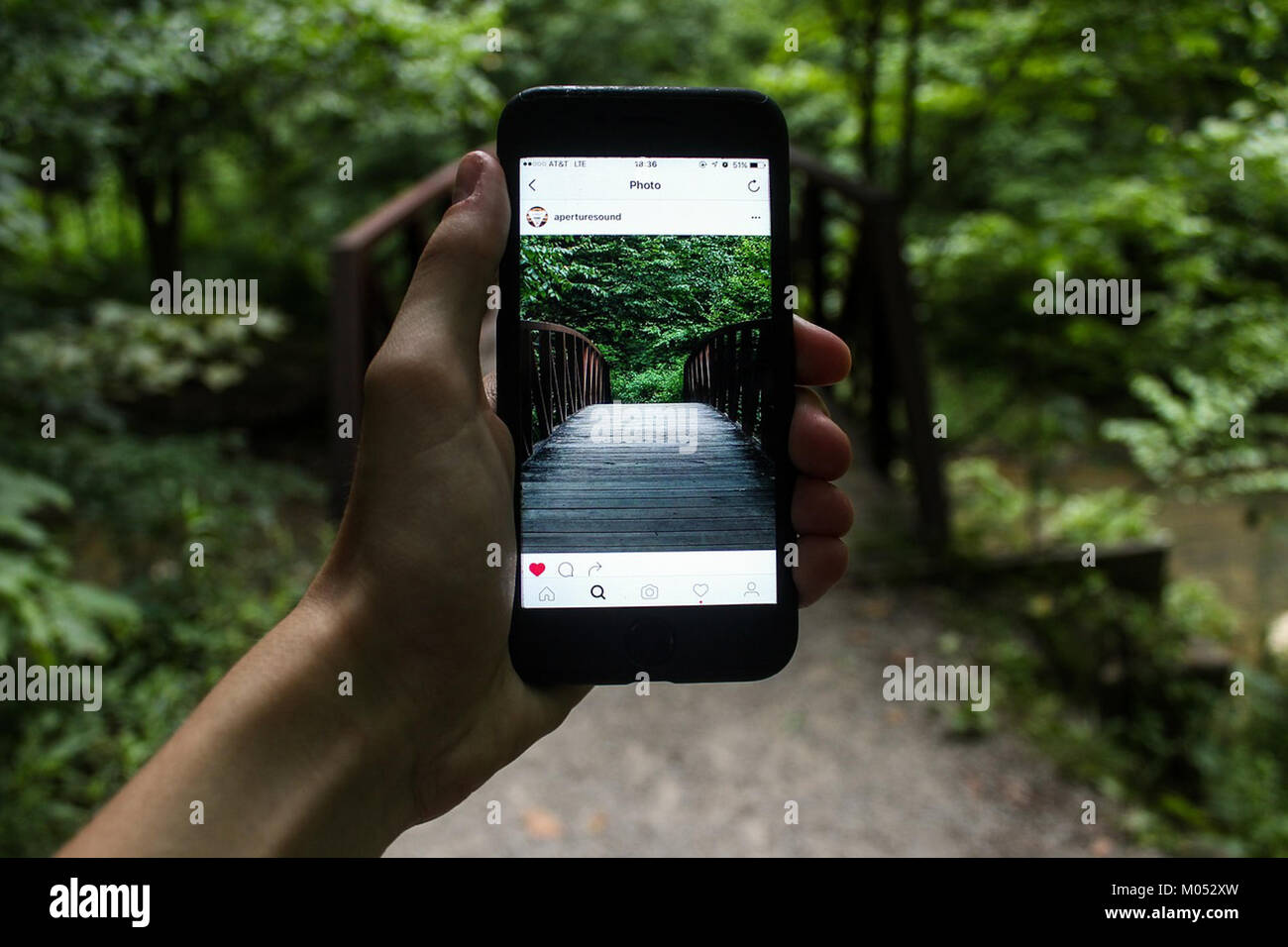 This image captures a close-up of a hand holding an iPhone with a gadget attached, possibly for macro photography. The image highlights the modern technology and the accessibility of advanced gadgets. Stock Photo