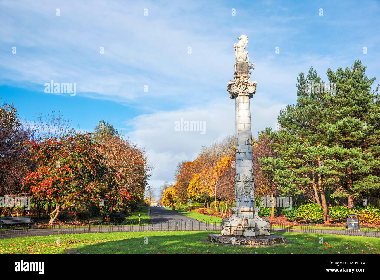 Unicorn at top of free-standing Ionic column at axis of park walkways in Springburn Park Glasgow showing the colours of Autumn. Stock Photo