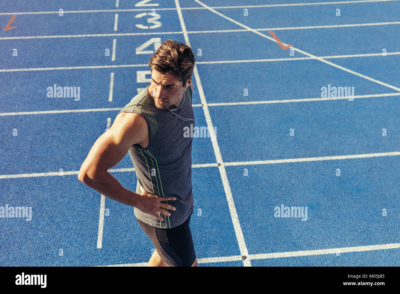 Athlete standing on a running track near the start line. Runner wearing ...