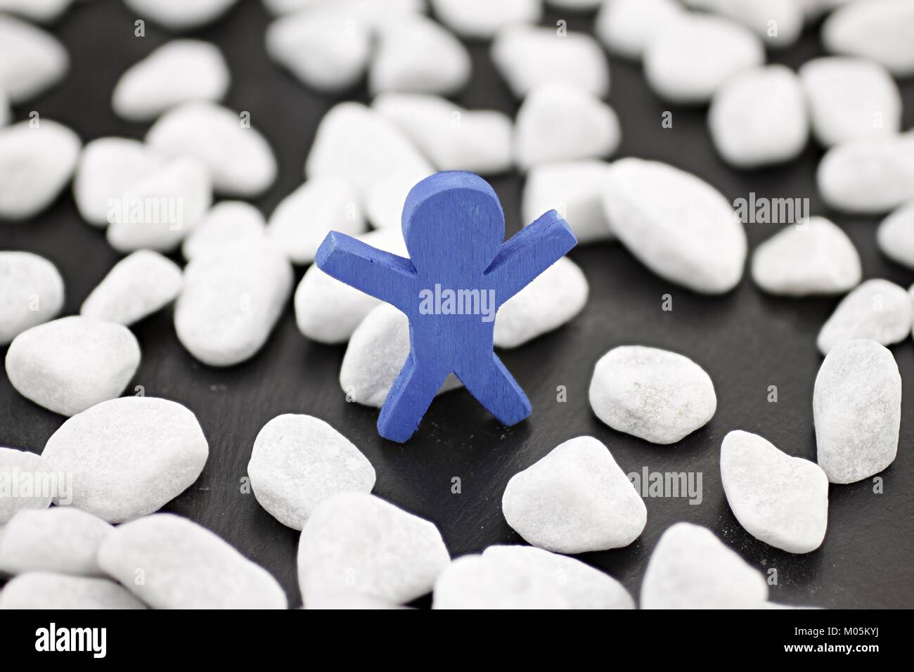 A blue male stands alone in a group of white pebbles Stock Photo