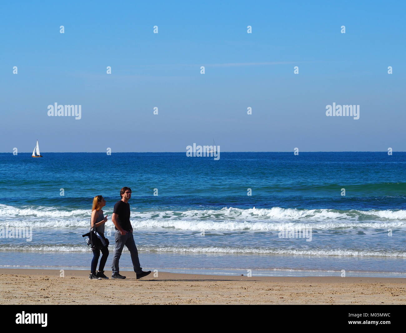 couple is strolling on a sandy beach Stock Photo