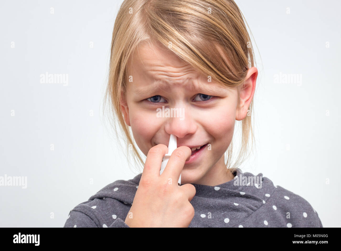 A girl overcomes his fear and uses nasal spray Stock Photo