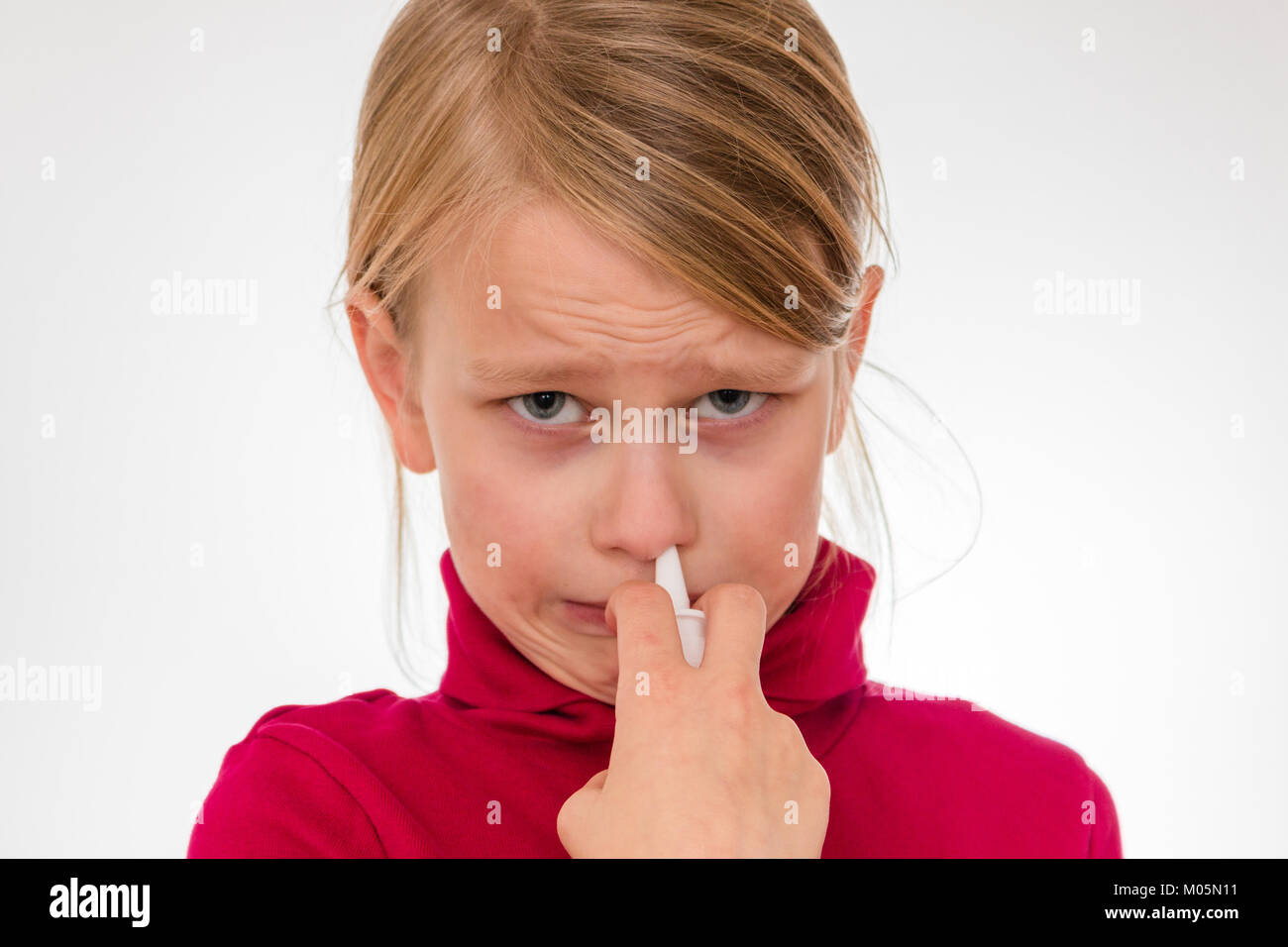 6 year old girl is using nose spray looking worried and frightened Stock Photo