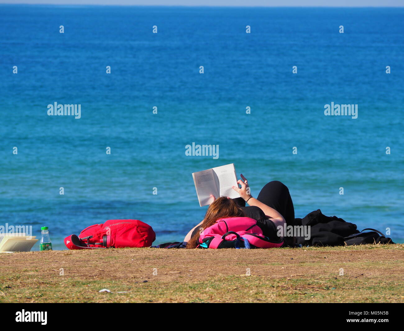 girl lying in the sun at the promenade near the beach in front of the sea on a perfect day with clear blue sky Stock Photo