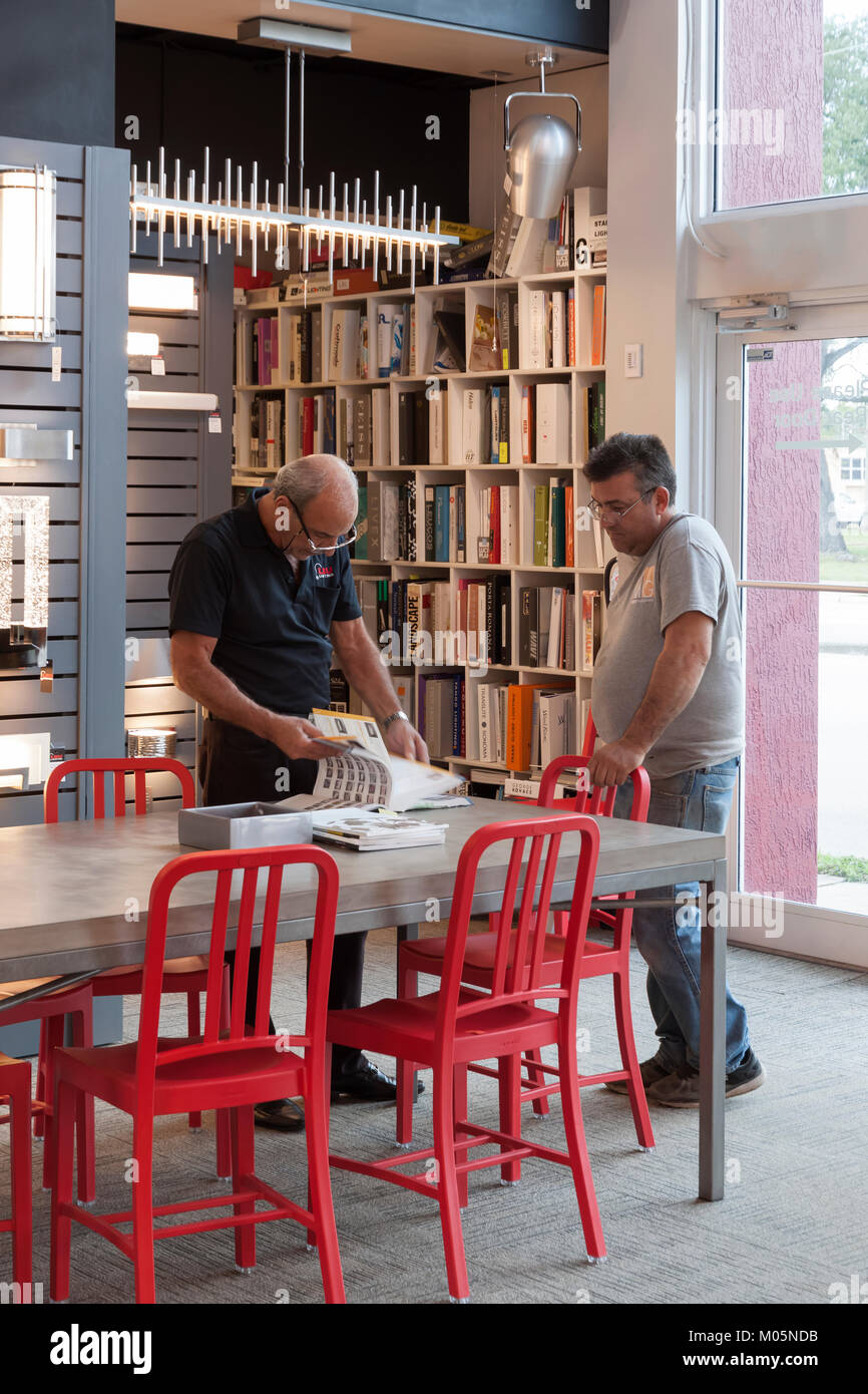 Salesperson in a retail lighting store servicing a customer by looking up information in a catalog. Stock Photo