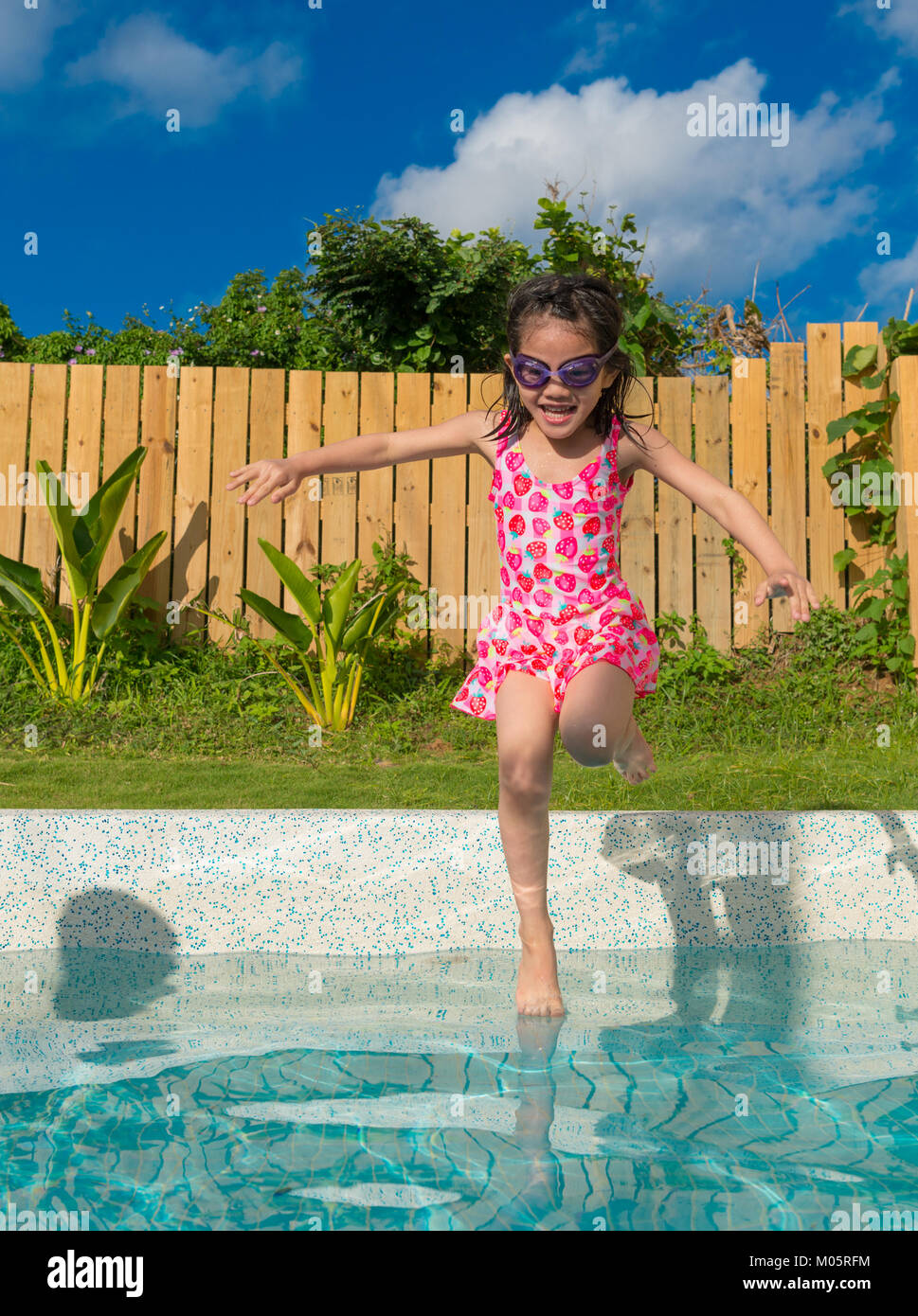 happy beautiful female kid children jumping into swimming pool to play