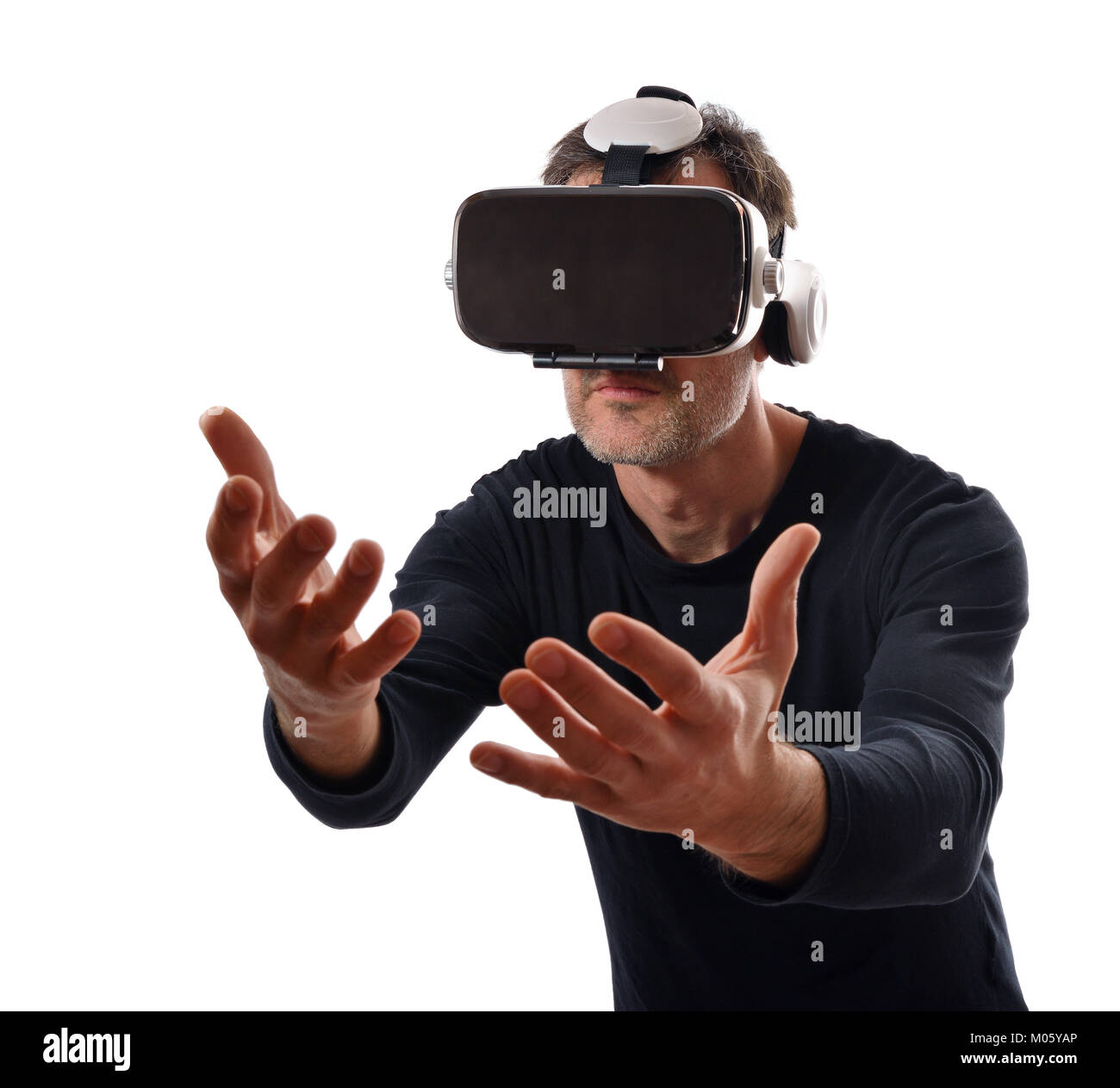 Serious man wearing black pullover and virtual reality glasses interacting with his hands in front. Isolated white Stock Photo