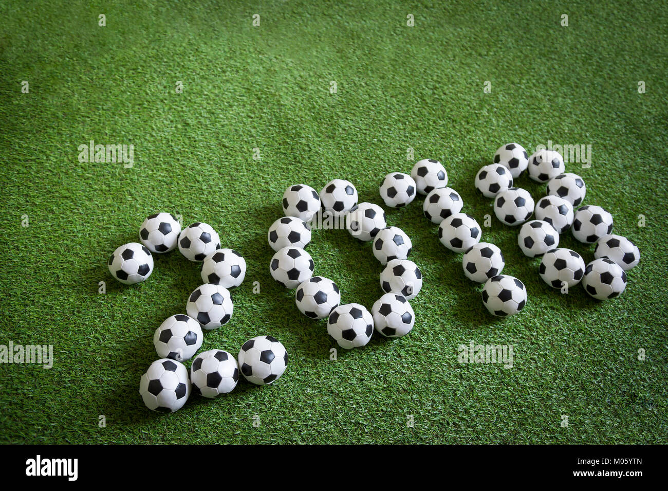 Sporty New Year 2018 message formed from footballs on green pitch