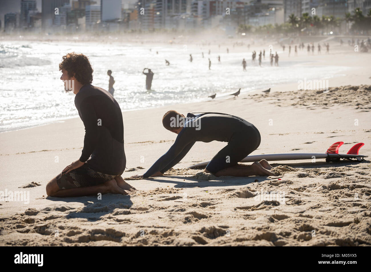 RIO DE JANEIRO - MARCH 20, 2017: Surfers stretch on the beach before heading into the waves at the surf break at Arpoador. Stock Photo