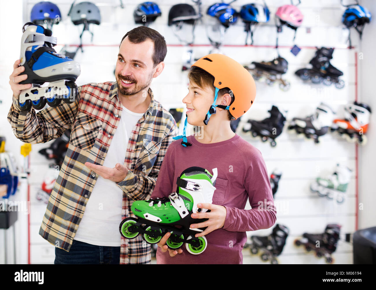 positive spanish male shop assistant helping boy to choose roller