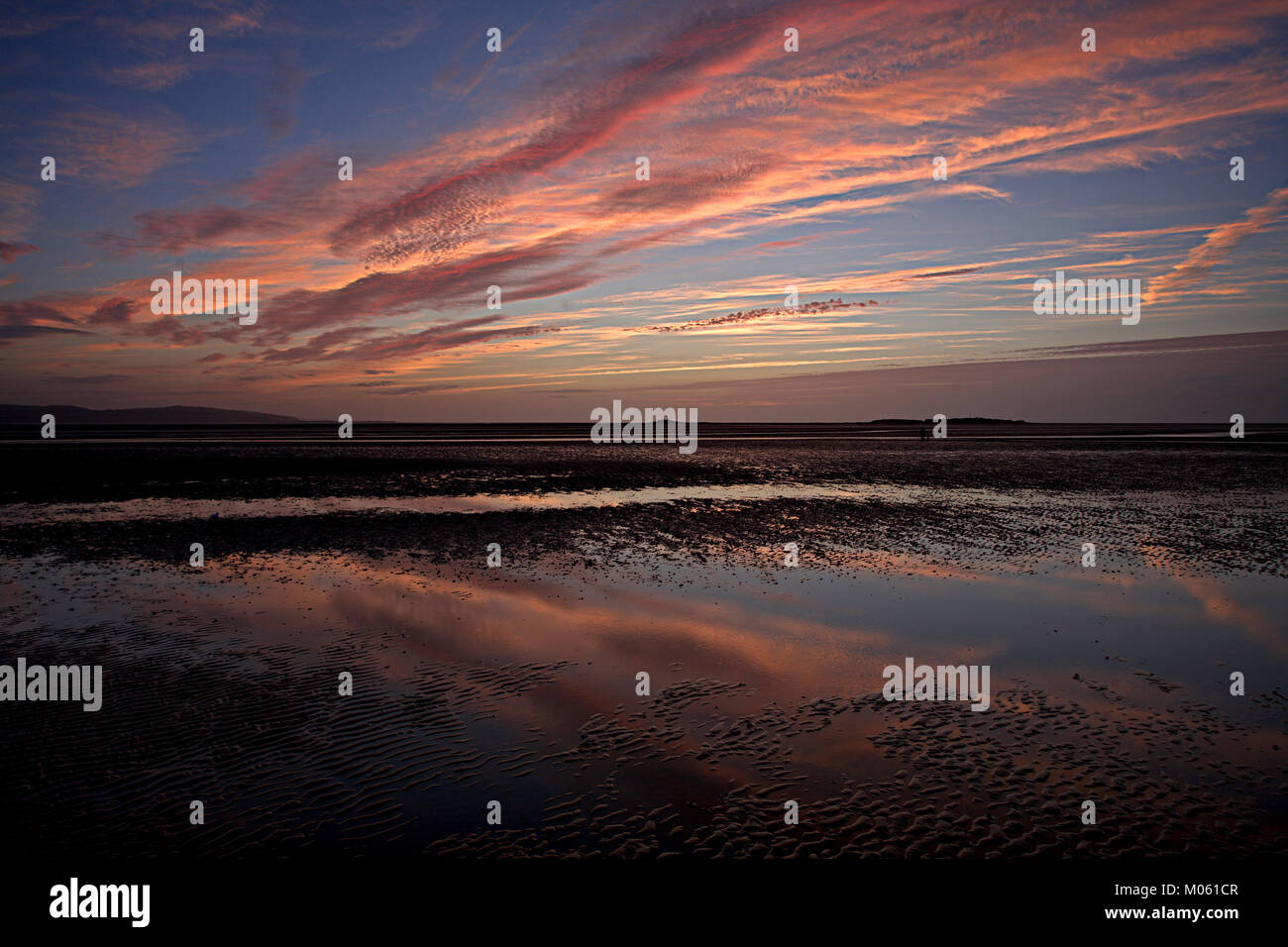 Colorful clouds reflecting in a pool of water on the sands at West Kirby, England at sunset Stock Photo