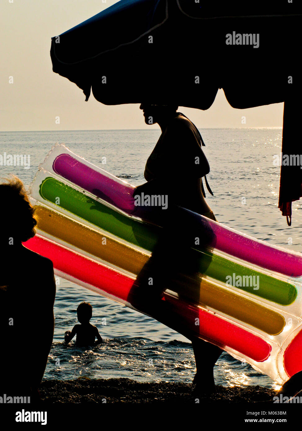 woman on the beach with inflatable mattress Stock Photo