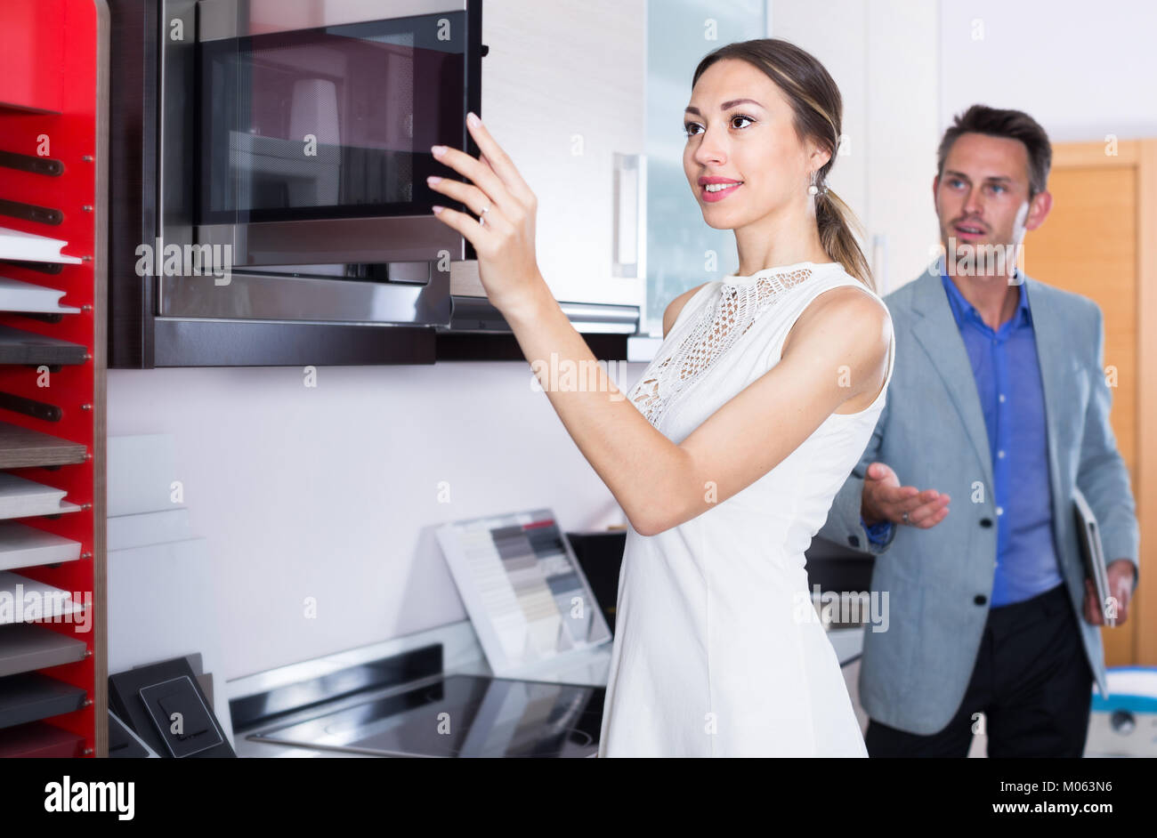 Couple is choosing new microwave in kitchen furnishing store. Stock Photo