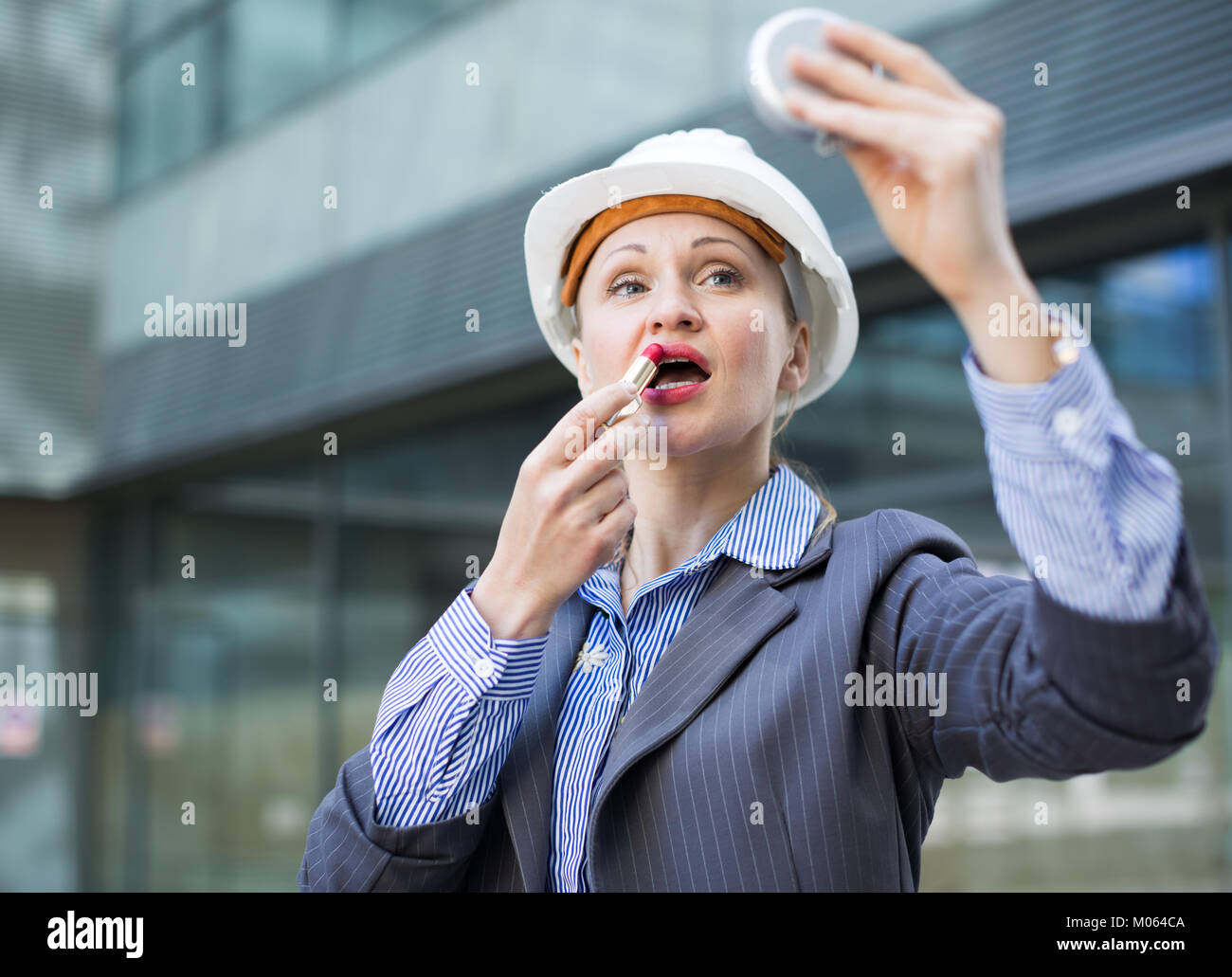 Employee woman in suit using lipstik and standing in helmet Stock Photo ...