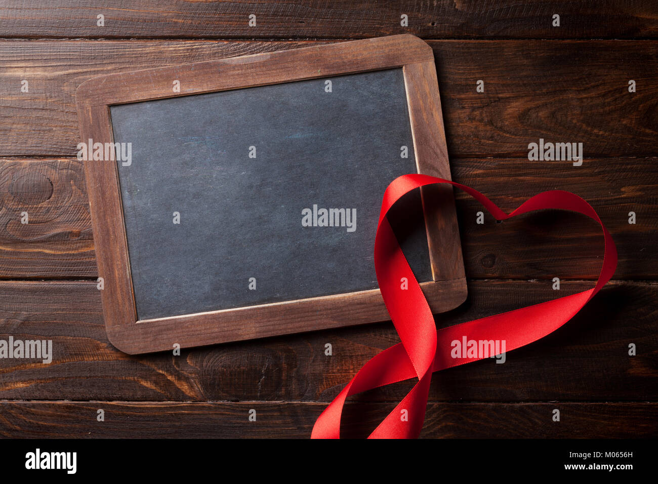 Valentines day greeting card with red heart ribbon on wooden table ...