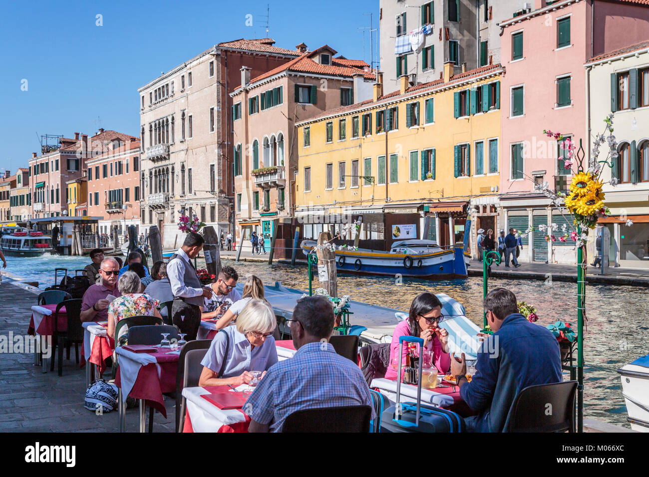 People eating at a canalside restaurant in Veneto, Venice, Italy, Europe. Stock Photo