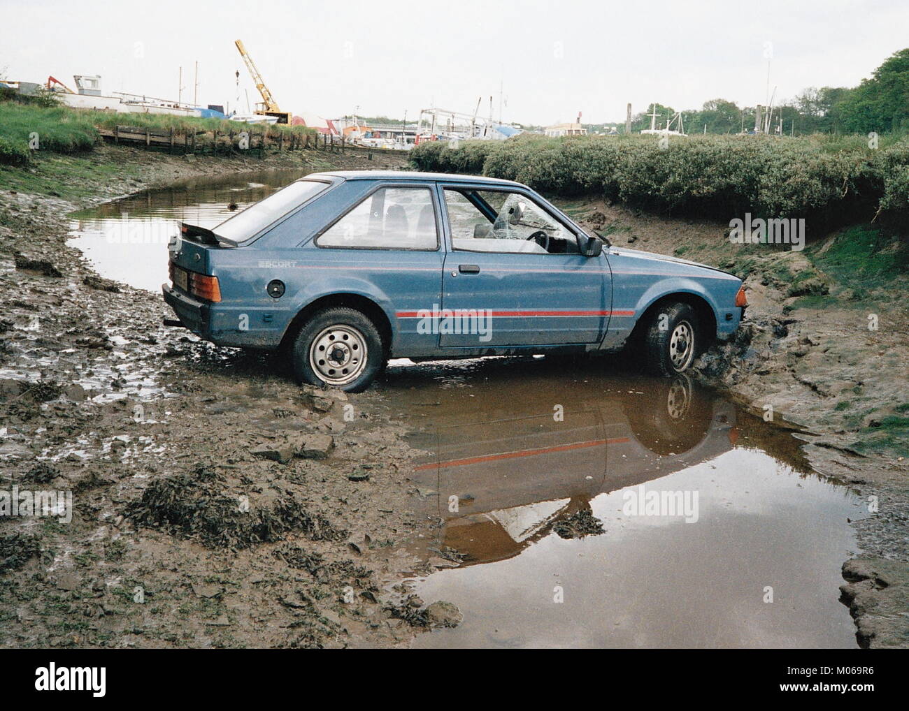 AJAXNETPHOTO. 1991.HAMBLE, ENGLAND. - UP THE CREEK. - A FORD ESCORT LIES IN A TIDAL RIVER CREEK AFTER COMING OFF THE ROAD.  PHOTO:JONATHAN EASTLAND/AJAX REF:TC6053 11 7 Stock Photo