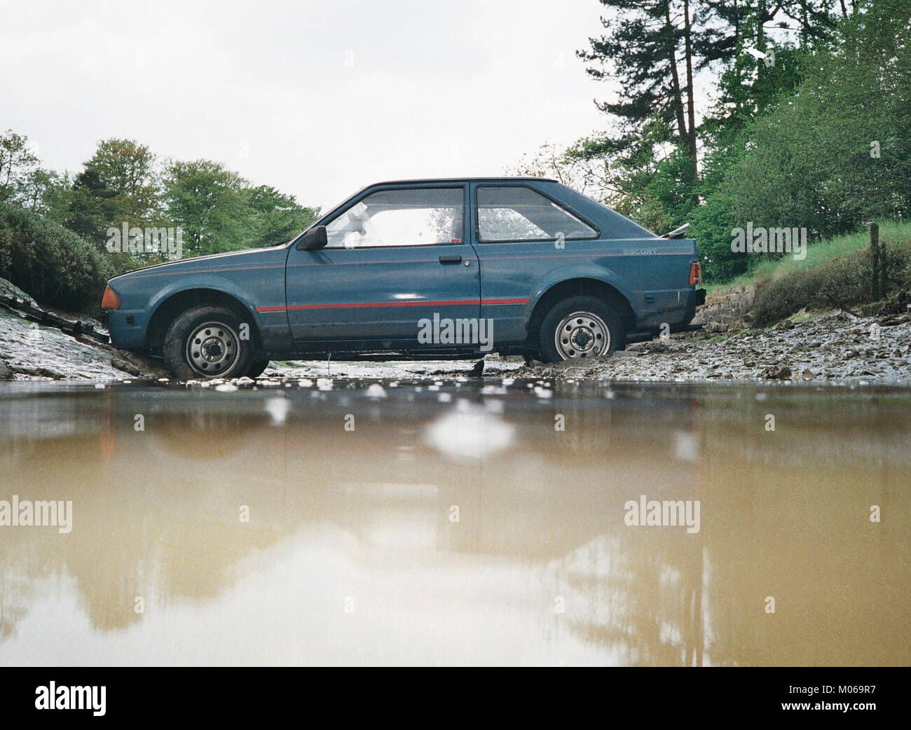 AJAXNETPHOTO. 1991.HAMBLE, ENGLAND. - UP THE CREEK. - A FORD ESCORT LIES IN A TIDAL RIVER CREEK AFTER COMING OFF THE ROAD.  PHOTO:JONATHAN EASTLAND/AJAX REF:TC6053 12 8 Stock Photo