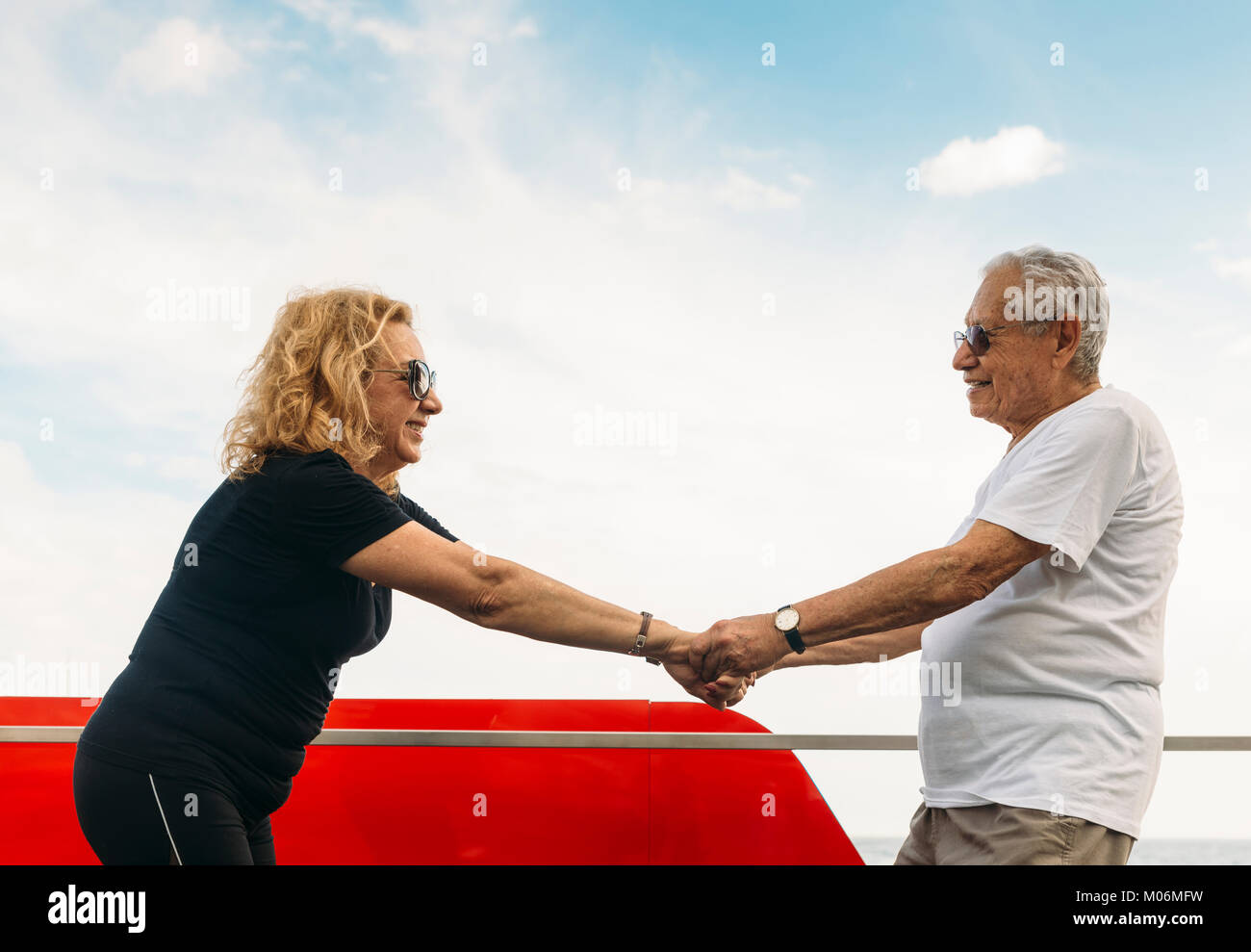 Model Released - Mature heterosexual couple stretching together against blue sky outdoors Stock Photo