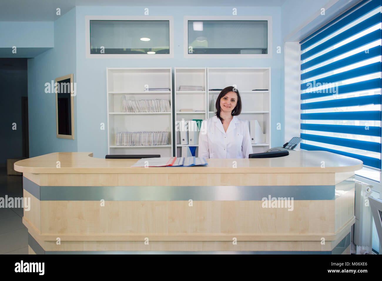 Young practitioner doctor working at the clinic reception desk, she is
