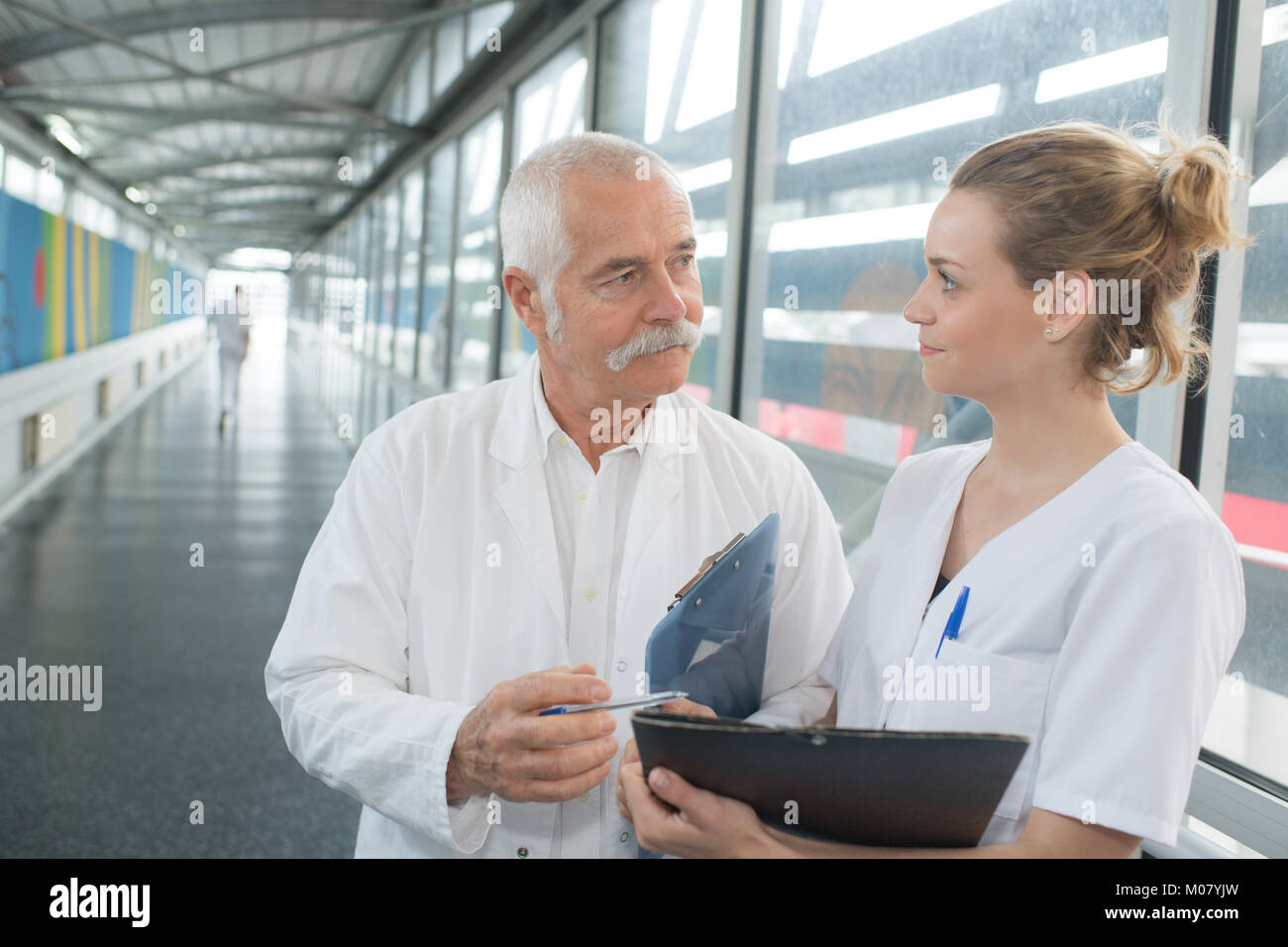 senior male doctor and female nurse in hospital corridor Stock Photo