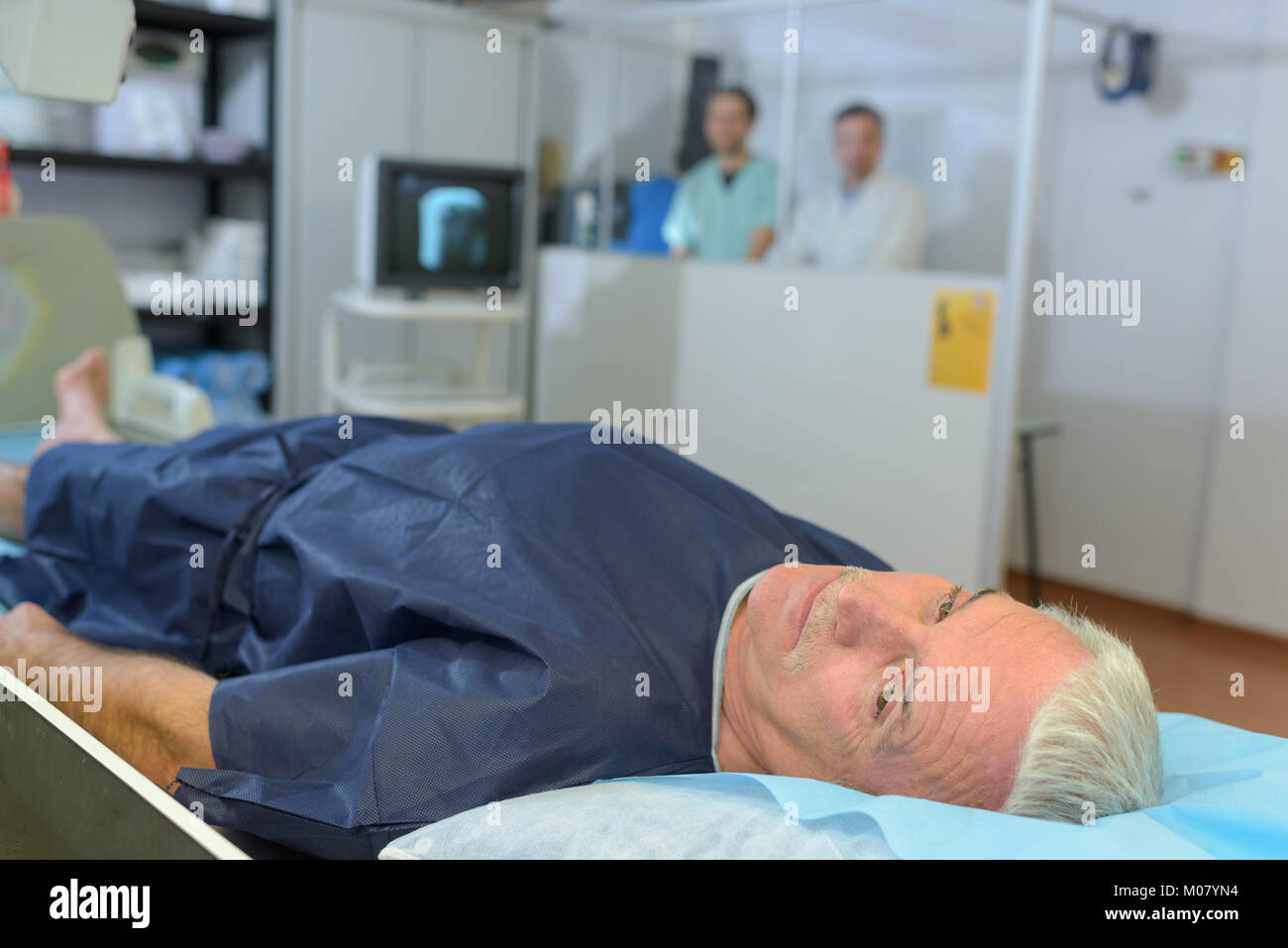 Patient having xray, medical staff shielded behind partition Stock Photo