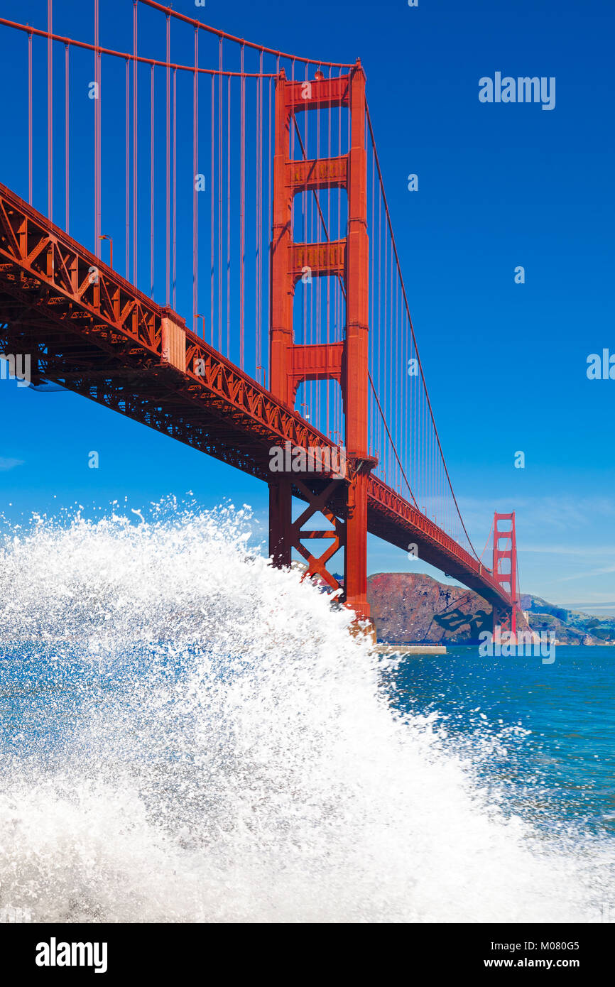 Golden Gate Bridge with a big white wave splash in the foreground. Stock Photo