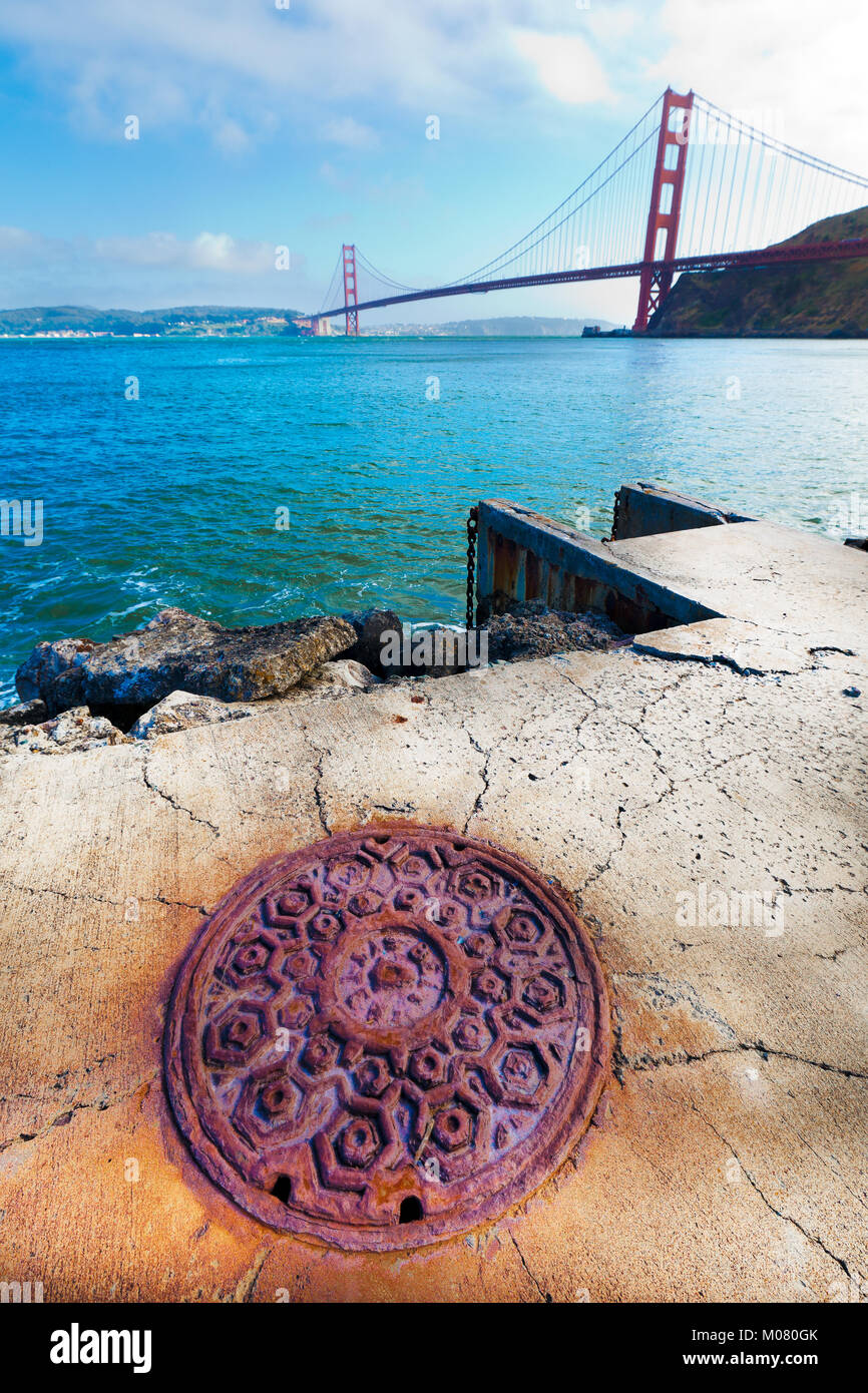 View of the Golden Gate Bridge and San Francisco from across the water in Sausalito. Ornate old iron manhole cover in the foreground. Stock Photo