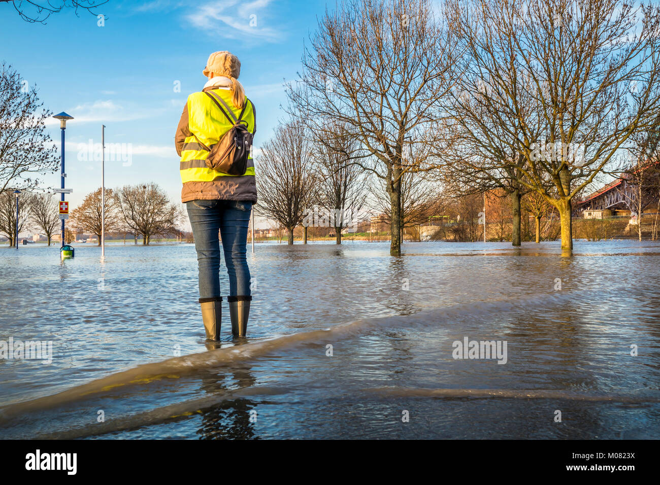 Lady standing in flooded street in wellys Stock Photo