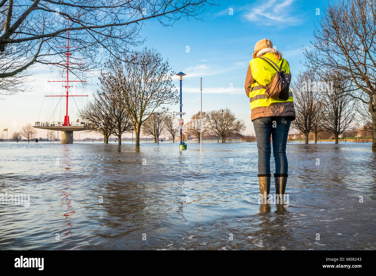Lady standing in flooded street in wellys Stock Photo
