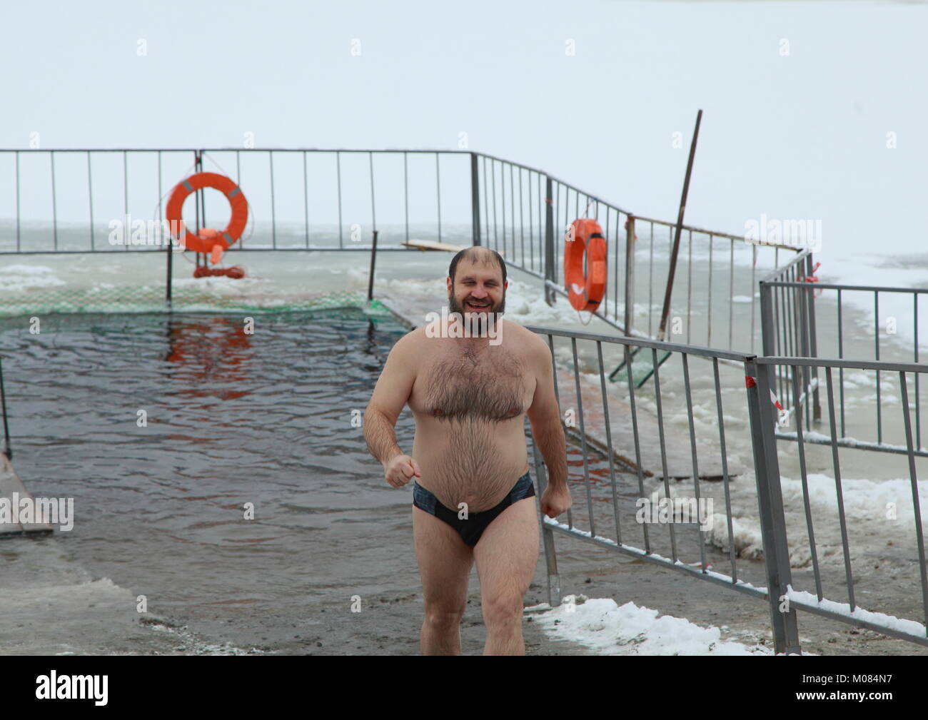 Epiphany in Russia. Male wanting to imitate Jesus Christ, three times, dipped in ice-cold Holy water and leaving the water shines with happiness. Stock Photo