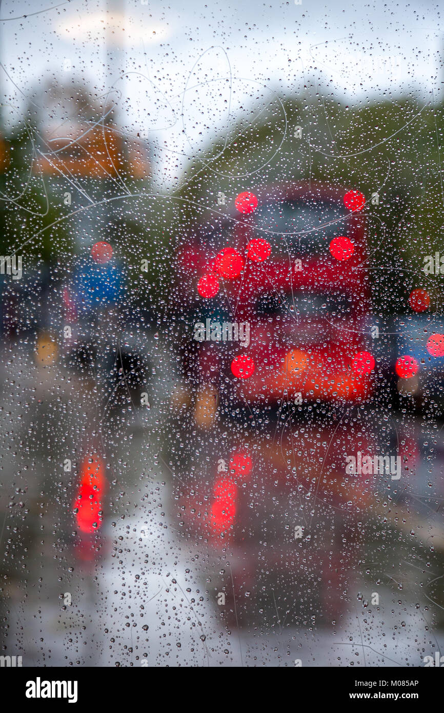 London traffic scene with Doubledecker bus seen through bus stop glass covered with rain drops - autumn rainy weather concept Stock Photo