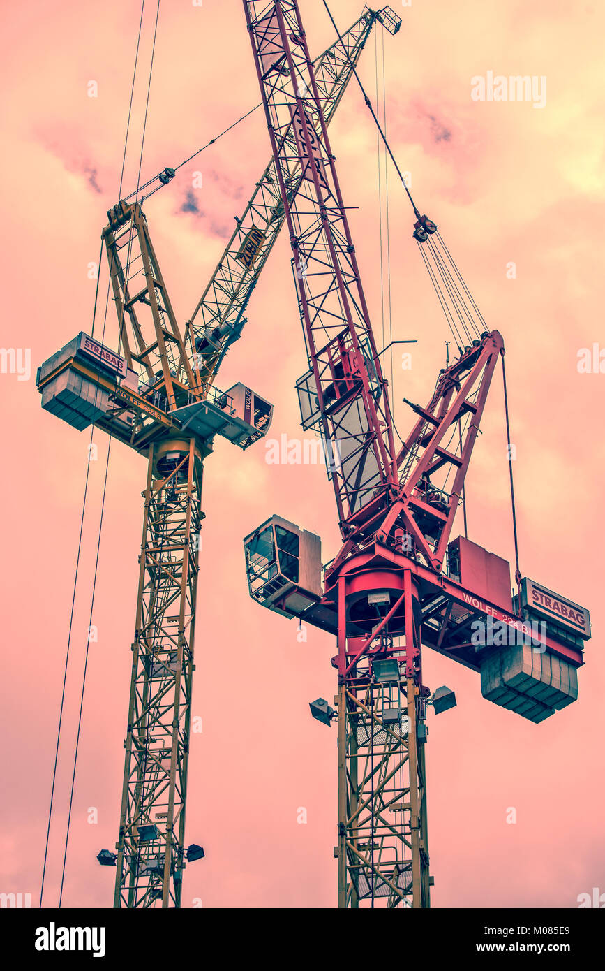 Two building cranes in front of red skyconstruction zone  Two building cranes in front of red sky Stock Photo