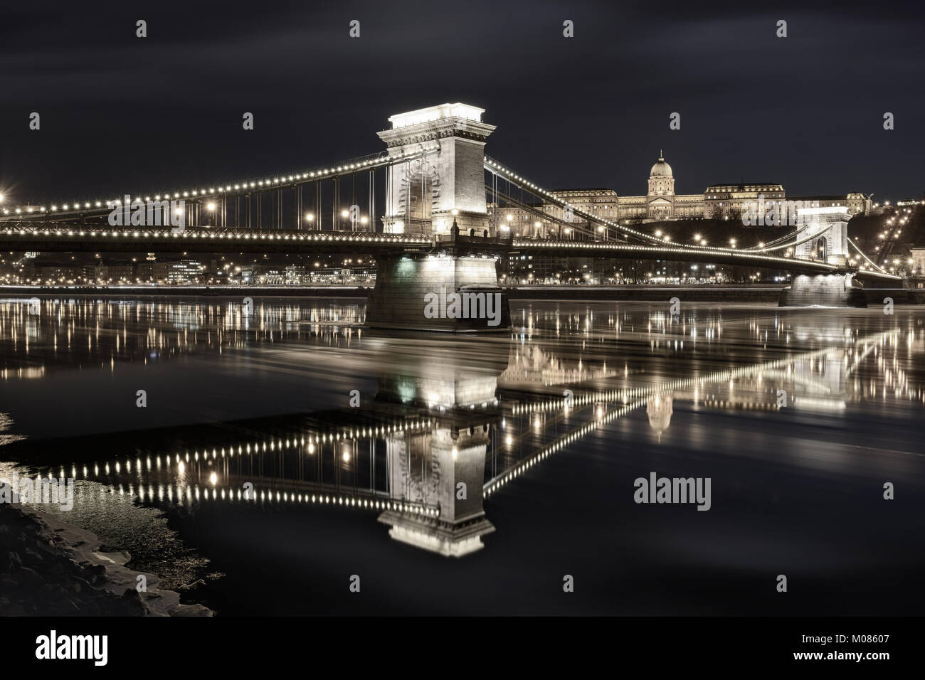 Szechenyi chain bridge against Buda Castle, moving ice floes on Danube river surface. Late night Stock Photo
