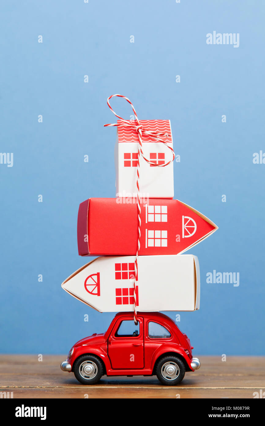 Toy car carrying a stack of houses. Moving house concept Stock Photo