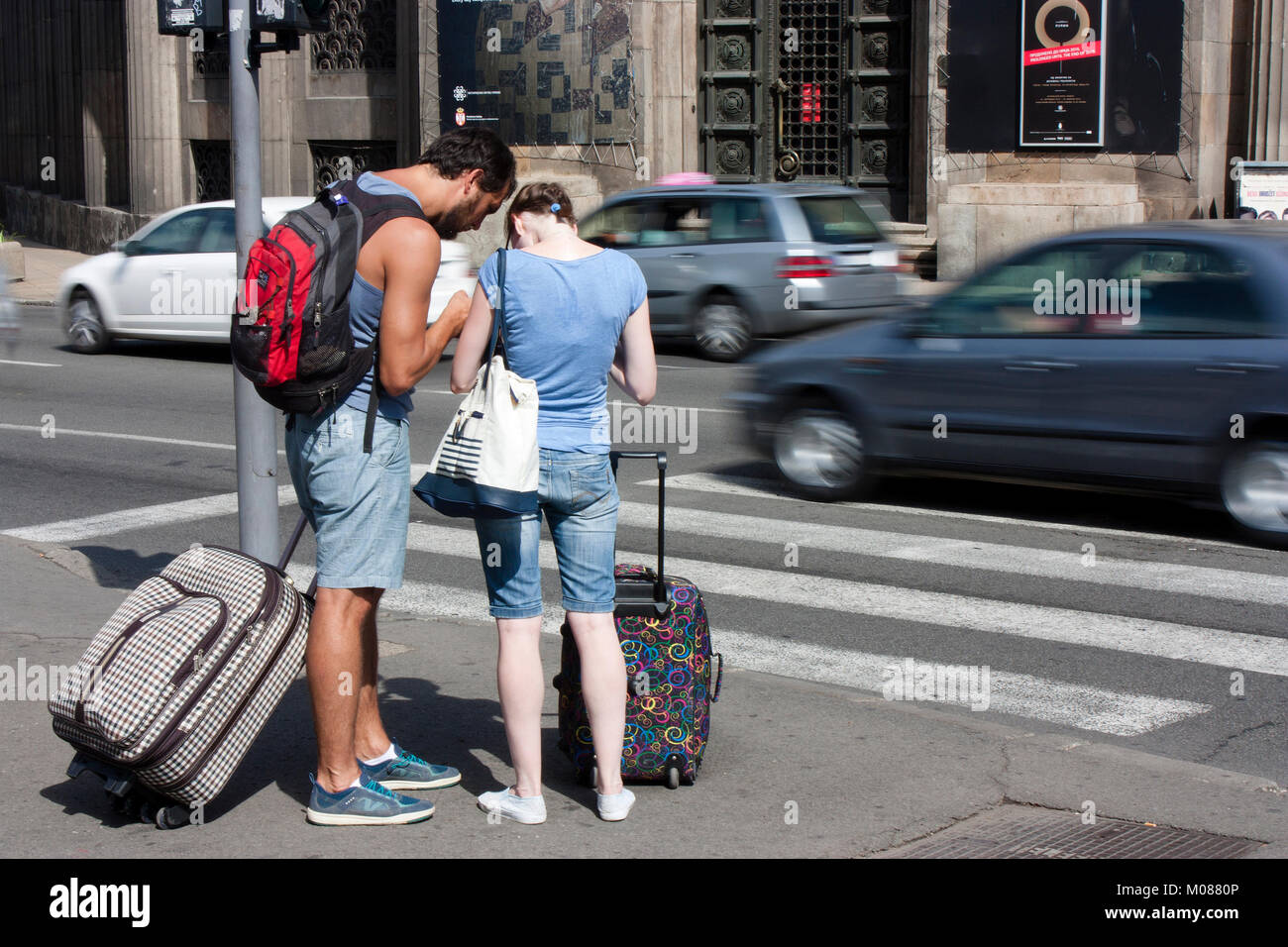 Belgrade, Serbia - September 17, 2017 : Young people traveling couple with rolling suitcases and backpacks trying to orientate and find their way and  Stock Photo