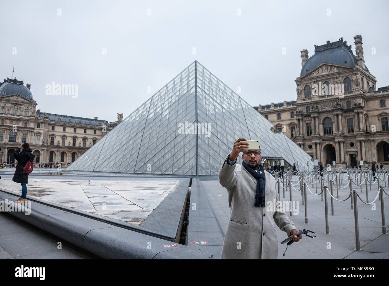 PARIS, FRANCE - DECEMBER 20, 2017: Tourist taking a selfie portrait in front of the Louvre Pyramid. Louvre pyramid (Pyramide du Louvre) is one of the  Stock Photo